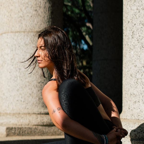 Person sitting cross-legged in a meditation pose facing a large window.